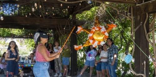 A blindfolded student tries to hit an orange piñata at Pitzer's outdoor classroom